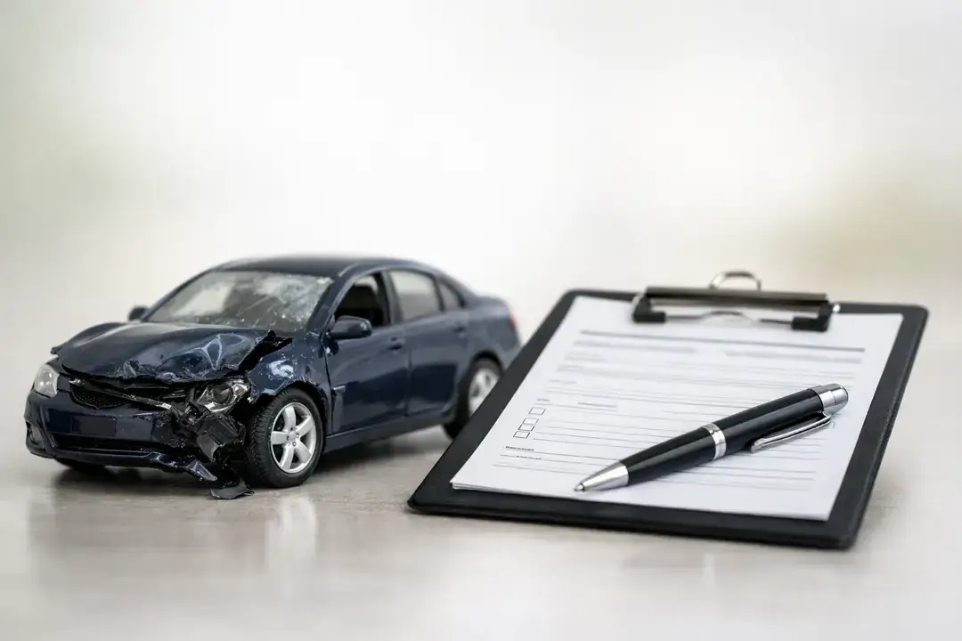 Damaged car model beside insurance form