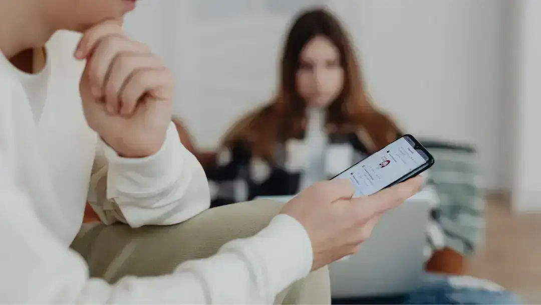 Person checking phone with woman behind