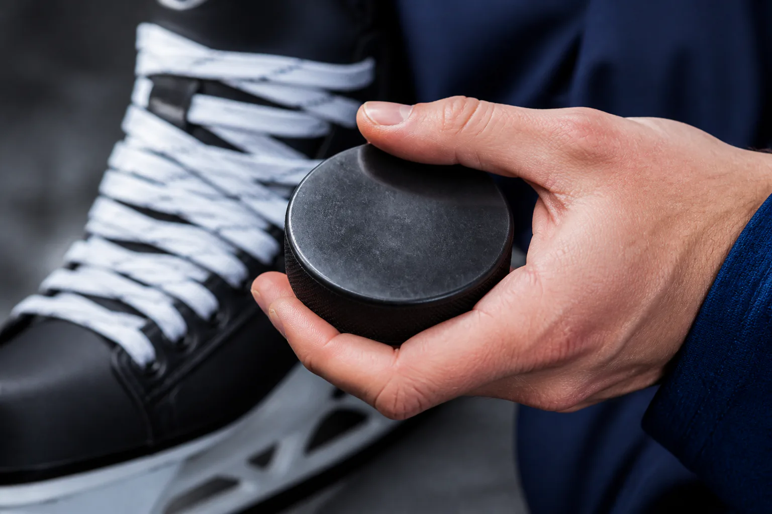 Hand holding hockey puck by skate