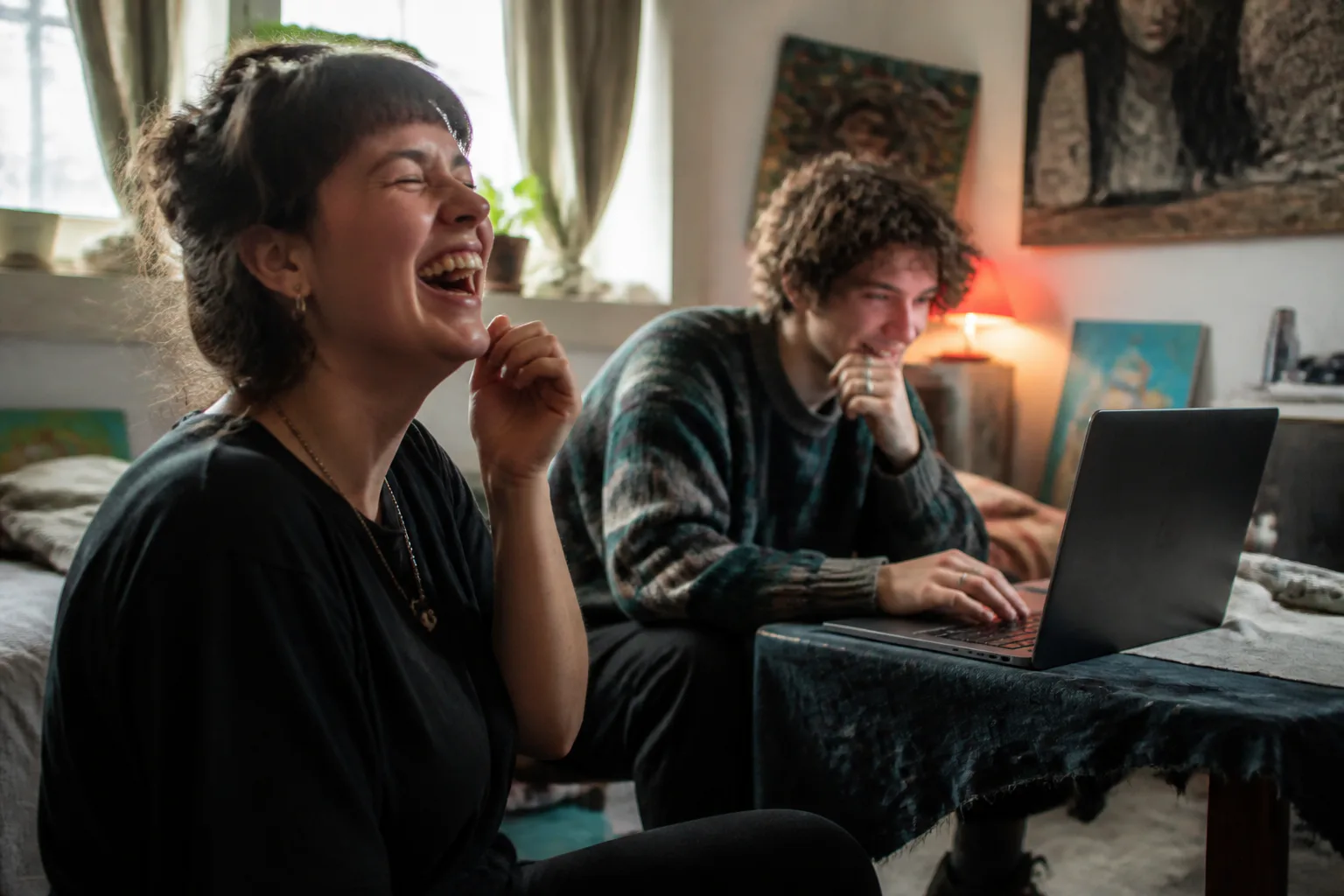 Two friends laughing over a laptop